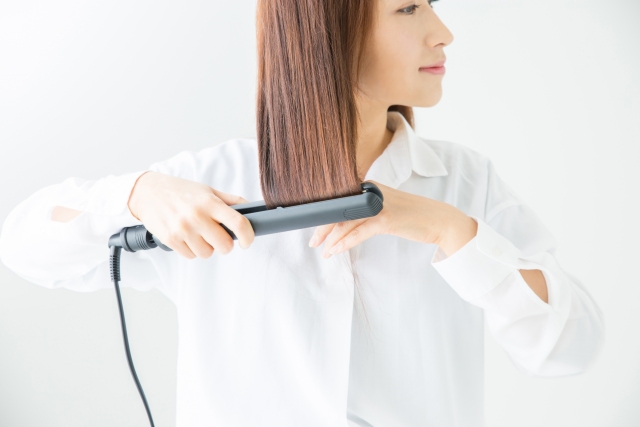 アイロンでヘアセットをしている女性