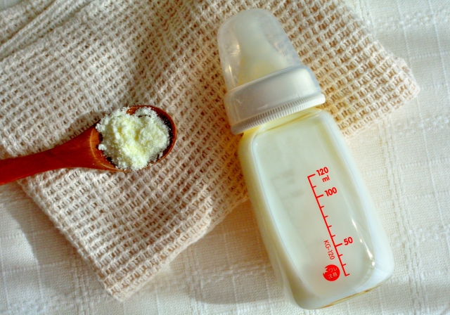 ミルク入りの哺乳瓶とスプーンの上に乗った粉ミルク