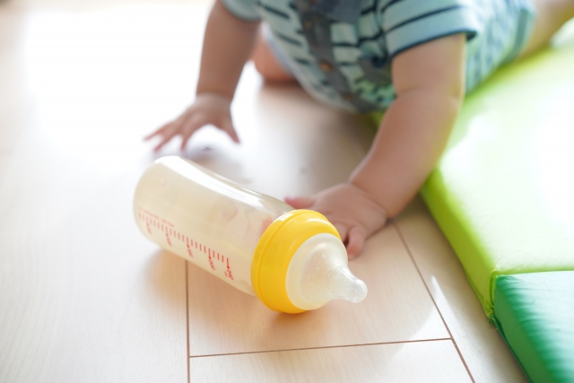 赤ちゃんの手元に転がる哺乳瓶