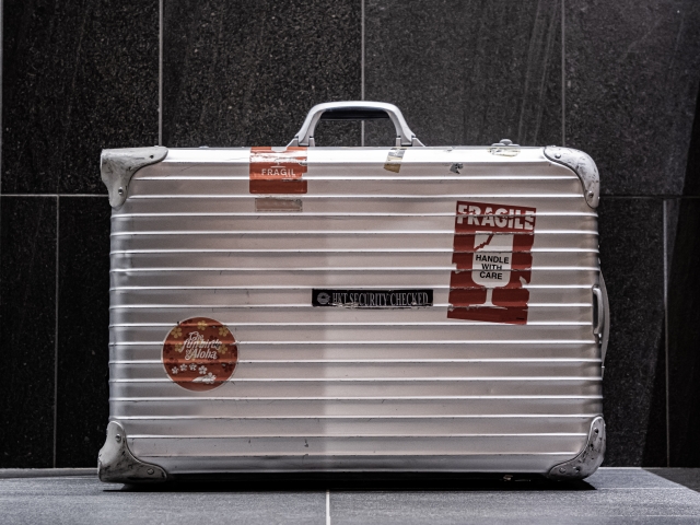 ステッカーが貼ってあり、横倒しになっているシルバーのスーツケース