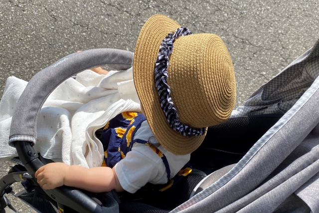 帽子をかぶりベビーカーに座っている子供