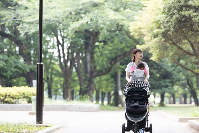 子供を抱っこしながらベビーカーを押している女の人