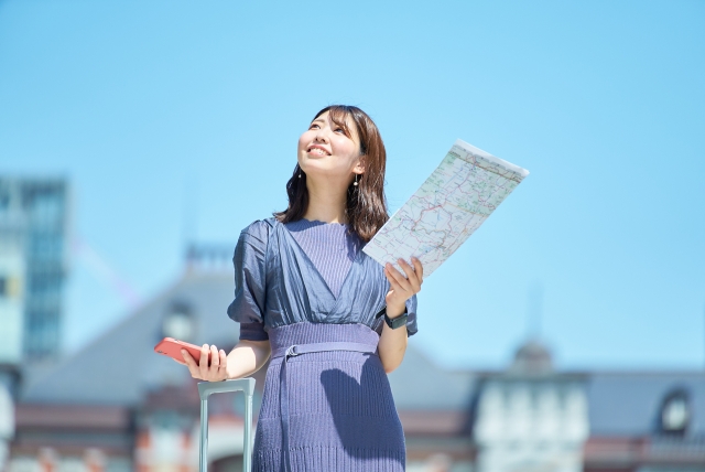 地図とスマホをもって上を見ている女性