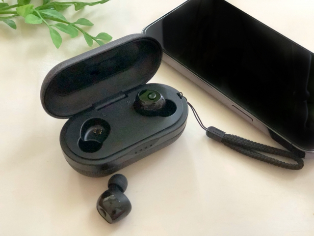 ケースに入っているカナル型のワイヤレスイヤホンとスマホ